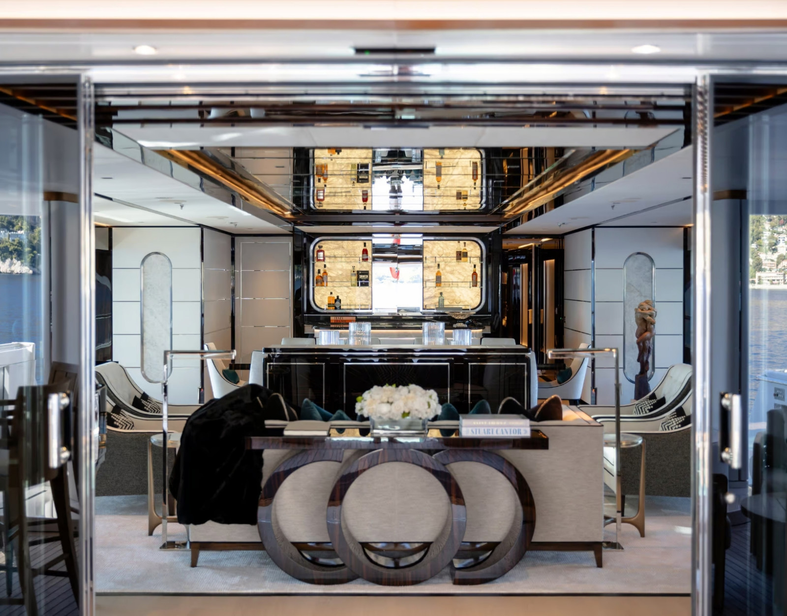 Benetti B.Now 67M main saloon interior featuring tailored luxury, mirrored details, elegant furnishings and a central bar area.
