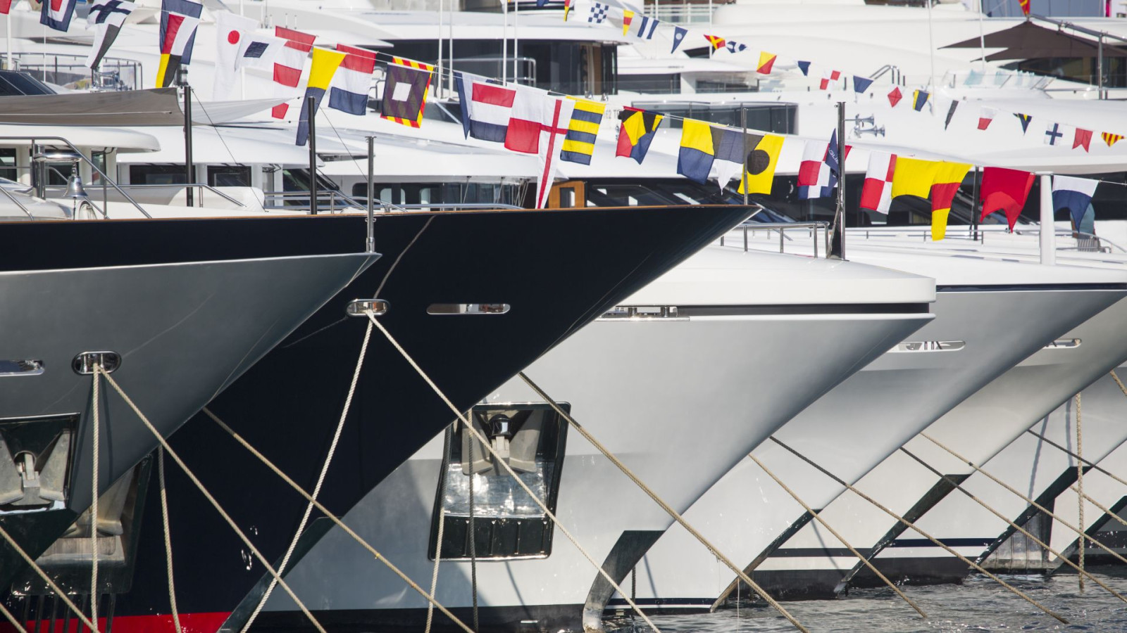 Superyachts flying international flags representing global yacht insurance coverage